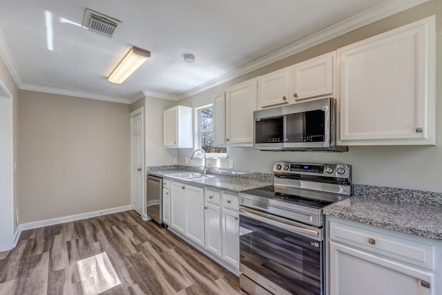 kitchen featuring visible vents, appliances with stainless steel finishes, white cabinets, and a sink