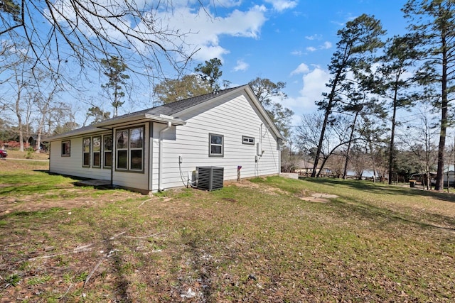 view of side of home with central AC and a lawn