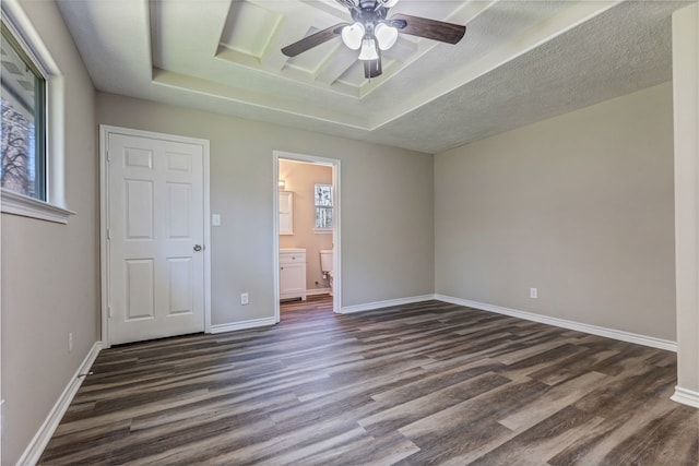 unfurnished bedroom with baseboards, dark wood finished floors, a textured ceiling, and a raised ceiling