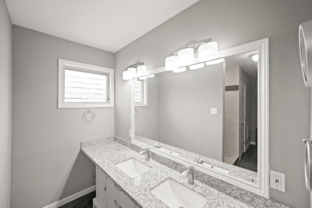 bathroom featuring double vanity, baseboards, and a sink