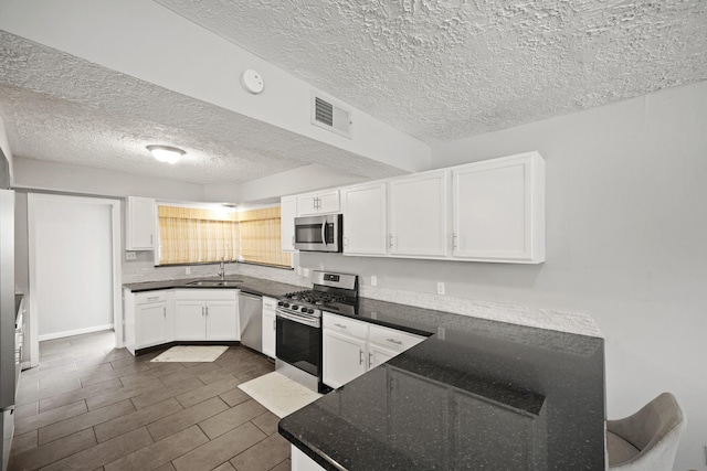 kitchen with visible vents, white cabinetry, stainless steel appliances, and a sink