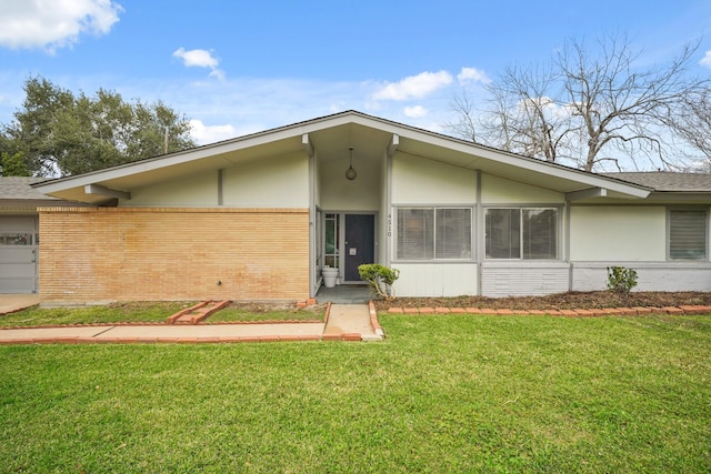 view of front of house featuring a front yard, brick siding, and stucco siding