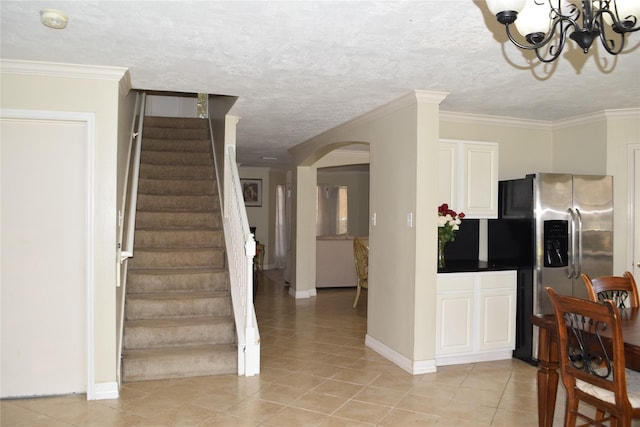 kitchen with arched walkways, light tile patterned floors, crown molding, and stainless steel fridge with ice dispenser