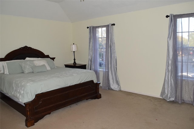 bedroom with light colored carpet, multiple windows, vaulted ceiling, and baseboards