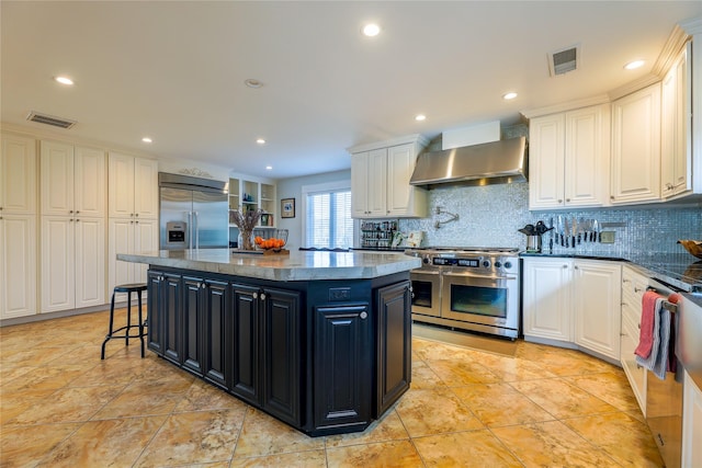 kitchen featuring visible vents, wall chimney exhaust hood, high quality appliances, dark cabinetry, and white cabinetry