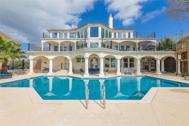 back of property with a fenced in pool, a balcony, ceiling fan, fence, and a patio area