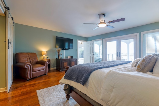 bedroom with french doors, hardwood / wood-style floors, a barn door, access to outside, and baseboards