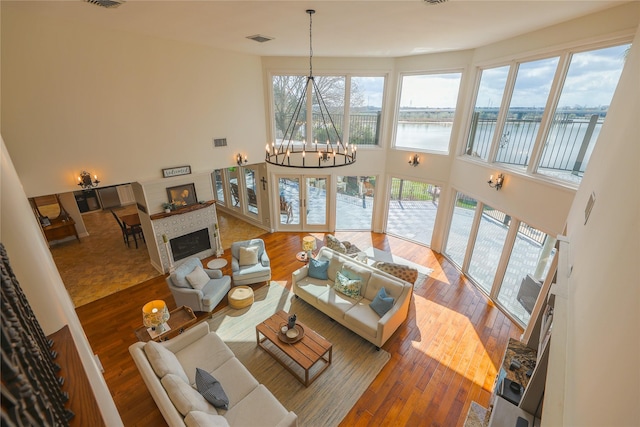 living area with a water view, visible vents, a healthy amount of sunlight, hardwood / wood-style floors, and a glass covered fireplace