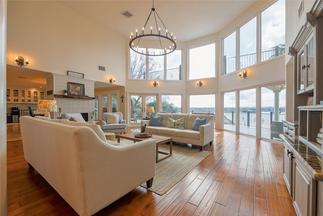 living room with a notable chandelier, a fireplace, visible vents, and wood finished floors