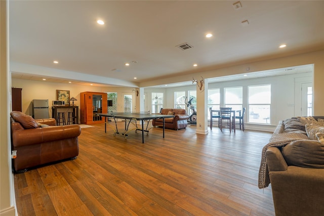 living room with recessed lighting, visible vents, and wood finished floors