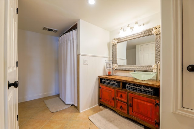 full bathroom with visible vents, a shower with shower curtain, a wainscoted wall, tile patterned floors, and vanity