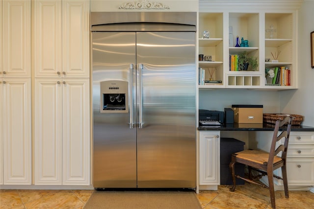 kitchen with white cabinets, built in refrigerator, and light tile patterned floors