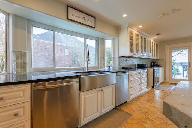 kitchen featuring stainless steel dishwasher, a sink, glass insert cabinets, and tasteful backsplash