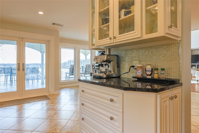 kitchen featuring dark stone countertops, french doors, light tile patterned flooring, and tasteful backsplash