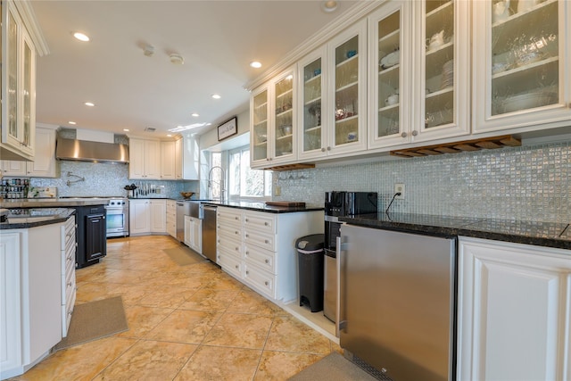 kitchen featuring recessed lighting, appliances with stainless steel finishes, backsplash, wall chimney exhaust hood, and dark countertops