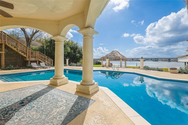 pool with stairs, a patio, and a water view