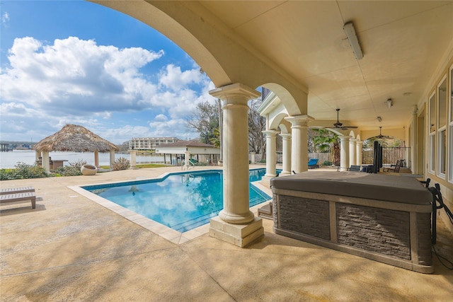 outdoor pool with a water view, a patio area, a ceiling fan, and a gazebo