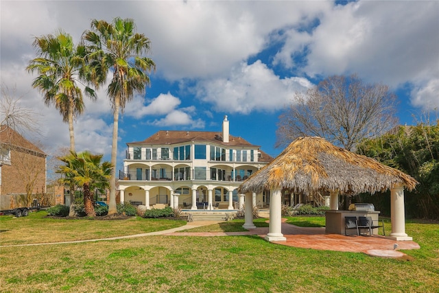 back of property with a yard, outdoor dry bar, and a balcony