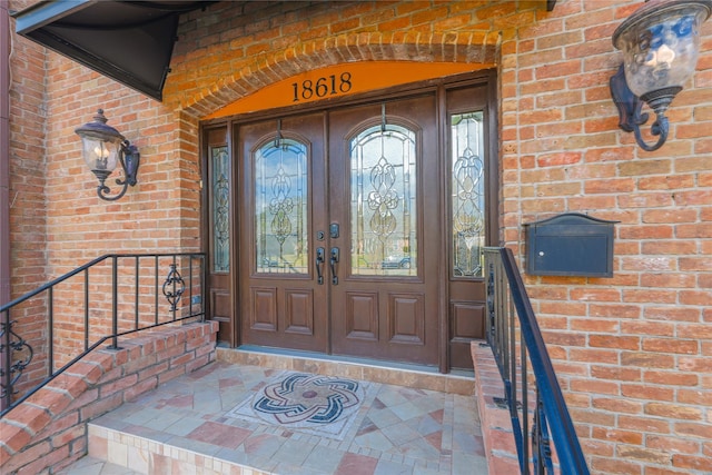 property entrance featuring brick siding and french doors