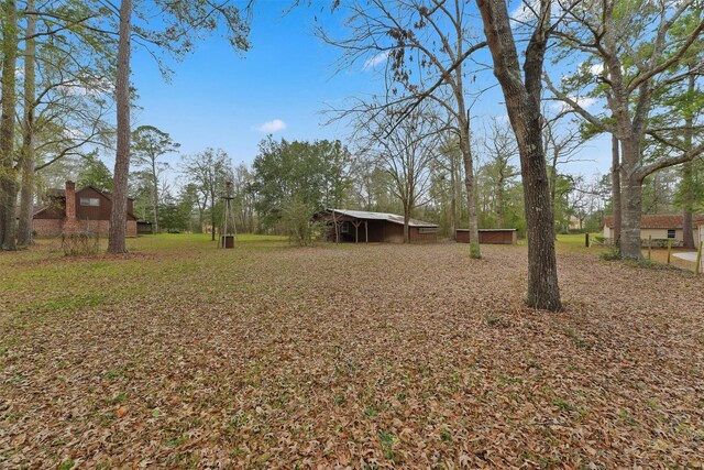 view of yard featuring a pole building, a carport, and an outdoor structure