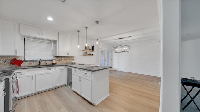 kitchen featuring beverage cooler, a peninsula, a sink, light wood-type flooring, and gas range