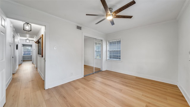 unfurnished bedroom with light wood-type flooring, visible vents, crown molding, and baseboards