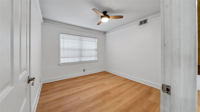 empty room featuring ceiling fan, visible vents, baseboards, light wood finished floors, and crown molding