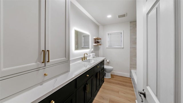 full bathroom with baseboards, visible vents, toilet, wood finished floors, and vanity