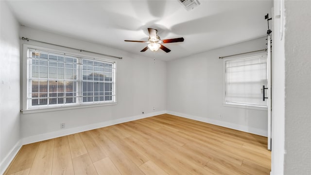 unfurnished room featuring a healthy amount of sunlight, baseboards, visible vents, and wood finished floors