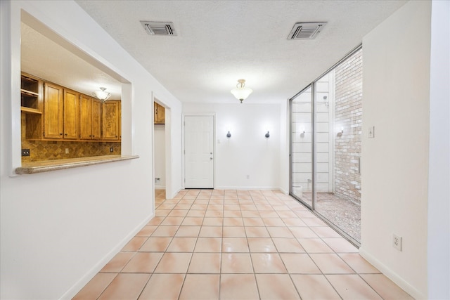 unfurnished room with light tile patterned flooring, visible vents, and a textured ceiling