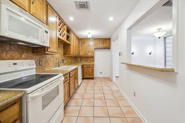 kitchen with visible vents, backsplash, brown cabinets, white appliances, and a sink