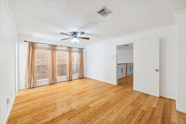 empty room with crown molding, light wood-style flooring, visible vents, and a textured ceiling