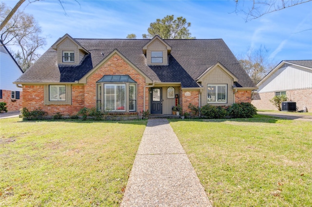 view of front of home with a shingled roof, a front yard, and central air condition unit