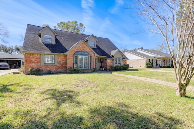 view of front of home with roof with shingles, a front lawn, and brick siding