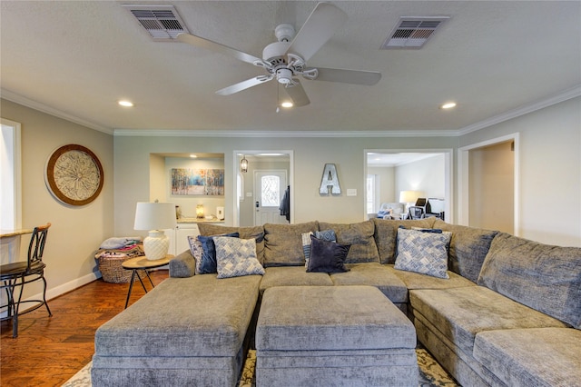 living room with dark wood-style flooring, visible vents, crown molding, and baseboards