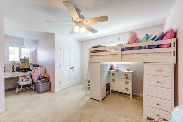 carpeted bedroom with a ceiling fan, a closet, a textured ceiling, and baseboards