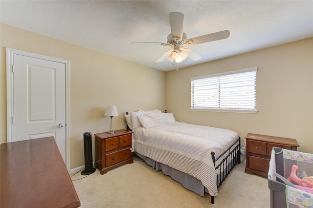 bedroom featuring a textured ceiling, baseboards, a ceiling fan, and light colored carpet