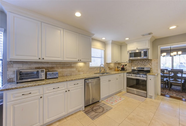 kitchen with white cabinetry, a notable chandelier, appliances with stainless steel finishes, and a sink