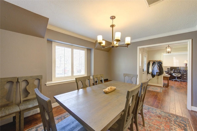 dining room featuring crown molding, visible vents, hardwood / wood-style floors, an inviting chandelier, and baseboards