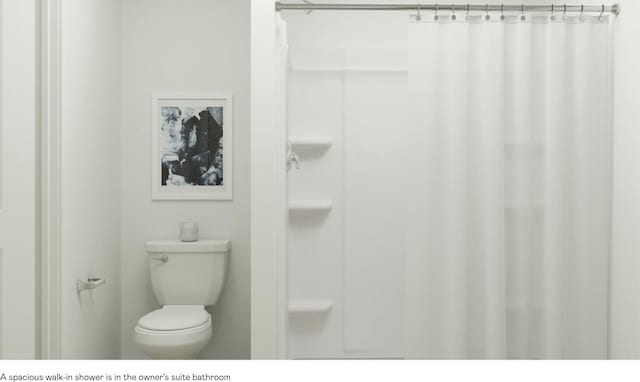 bathroom with toilet and a shower with shower curtain