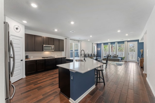 kitchen with open floor plan, appliances with stainless steel finishes, dark wood-type flooring, and a sink