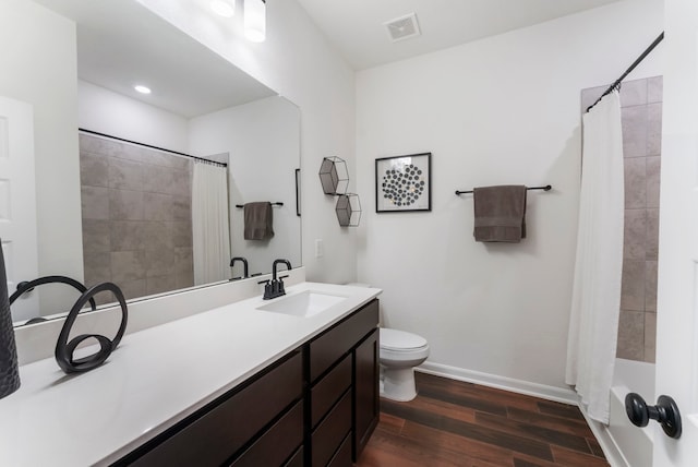 bathroom featuring visible vents, toilet, vanity, wood finished floors, and baseboards