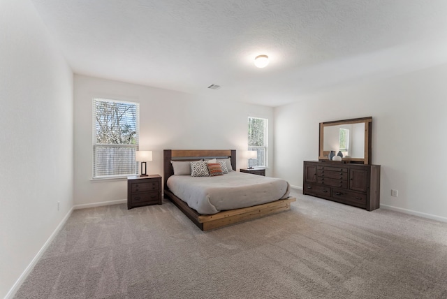 carpeted bedroom featuring visible vents, baseboards, and a textured ceiling