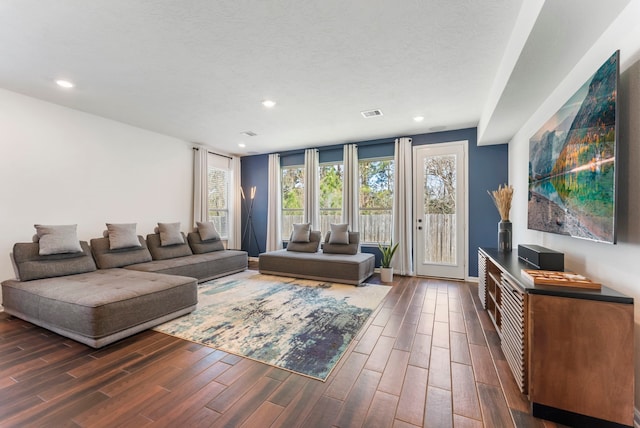 living area with a textured ceiling, visible vents, dark wood-type flooring, and recessed lighting