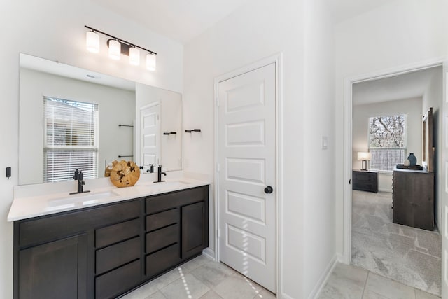 bathroom with double vanity, tile patterned flooring, baseboards, and a sink