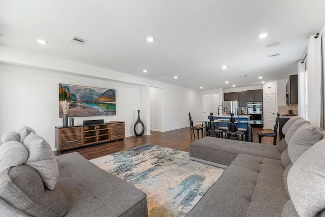 living area with visible vents, dark wood-style flooring, and recessed lighting