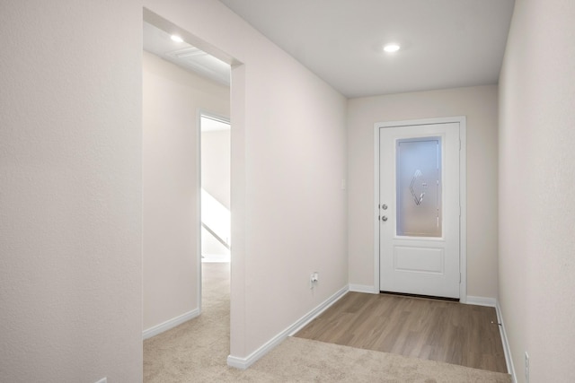 doorway with carpet, wood finished floors, and baseboards