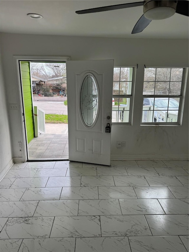 foyer with marble finish floor, ceiling fan, and baseboards