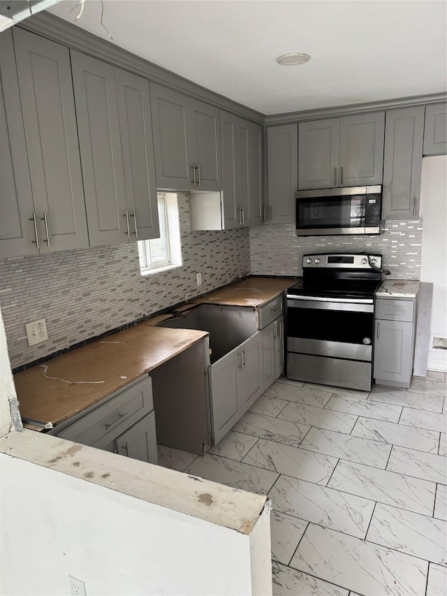 kitchen with marble finish floor, stainless steel appliances, and gray cabinetry