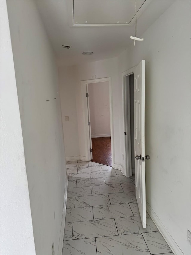 hall featuring marble finish floor, attic access, and baseboards